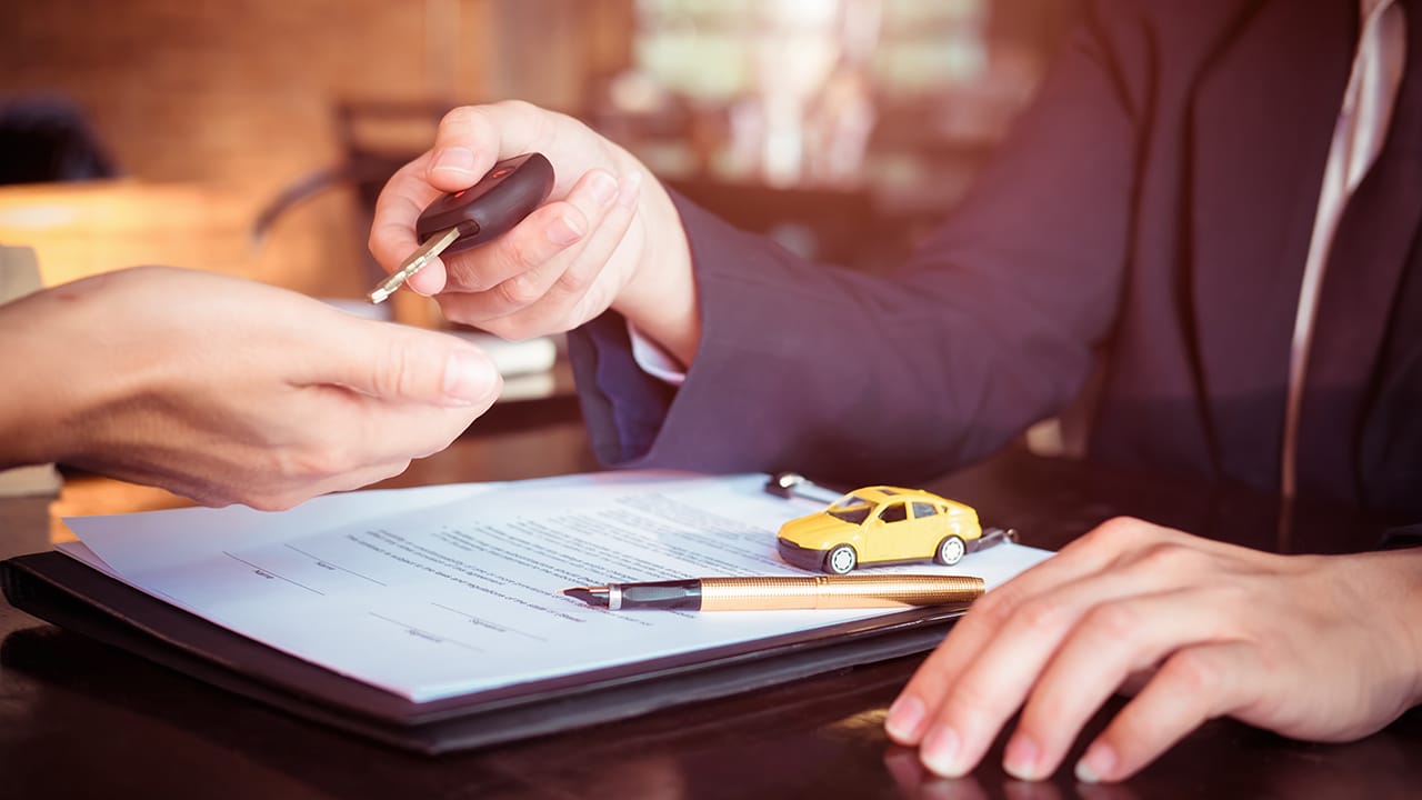 Car salesman holding key to his client after signing contract,concept for sale car,insurance with car, moving car or renting car